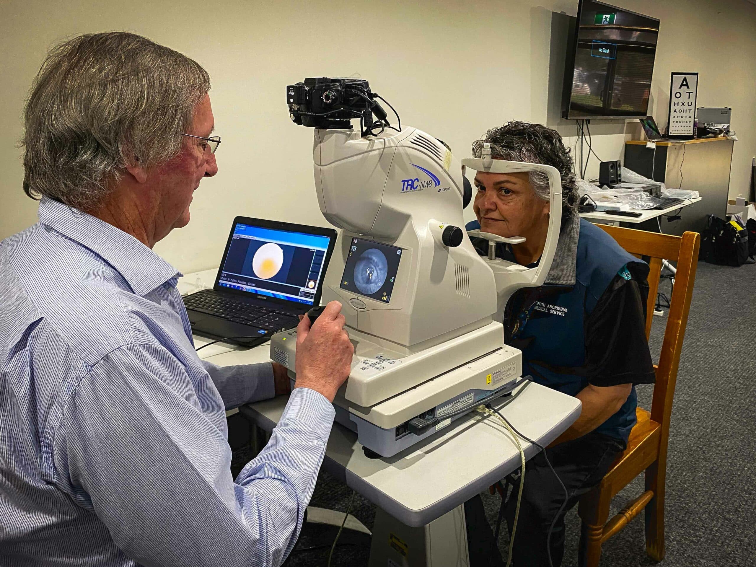 Associate Professor Geoffrey Painter examining the Griffith Aboriginal Medical Service CEO, Stacey O’Hara, with a retinal camera.